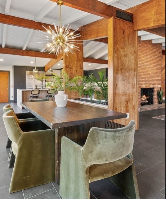 Dining room with exposed walnut beams, brick fireplace and a brass starburst chandelier