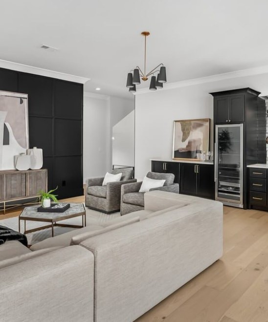 Living room wrapped in black cabinetry with a pale sectional on white oak